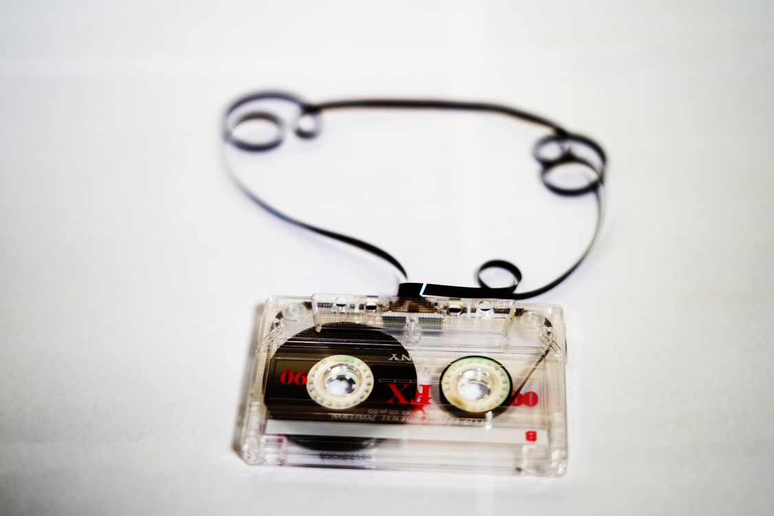 An audio cassette tape with tape spooled out, on a white background
